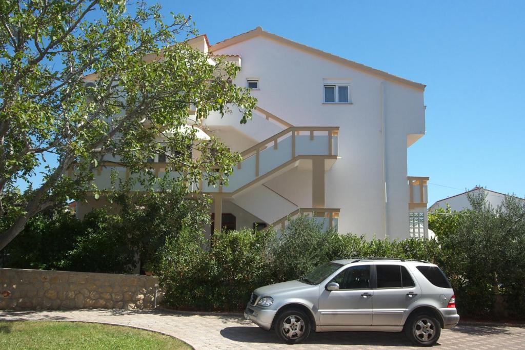 Srebrny SUV zaparkowany przed domem w obiekcie Apartments Novalja w Novalji