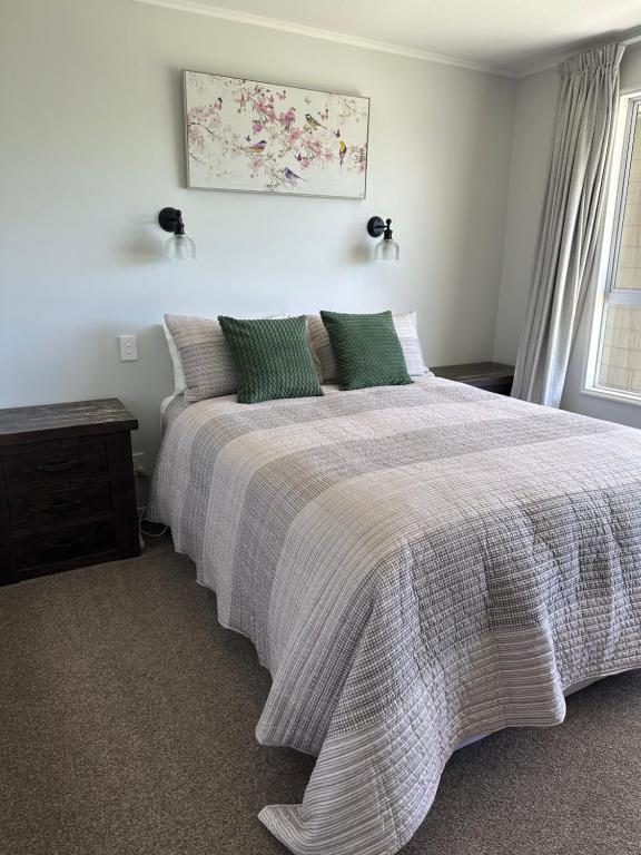 a bedroom with a large bed with green pillows at Cosy & close to town in Te Anau