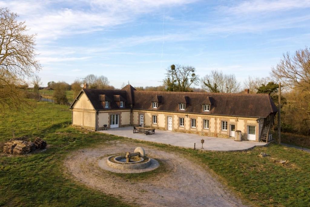 an old house with a fountain in front of it at La longère de Guitôt in La Ferté en Ouche