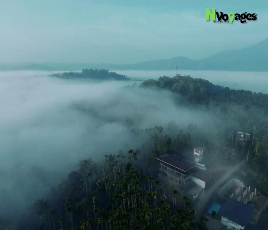 an overhead view of a fog covered hill with a city at Nvoyages Wayanad in Wayanad