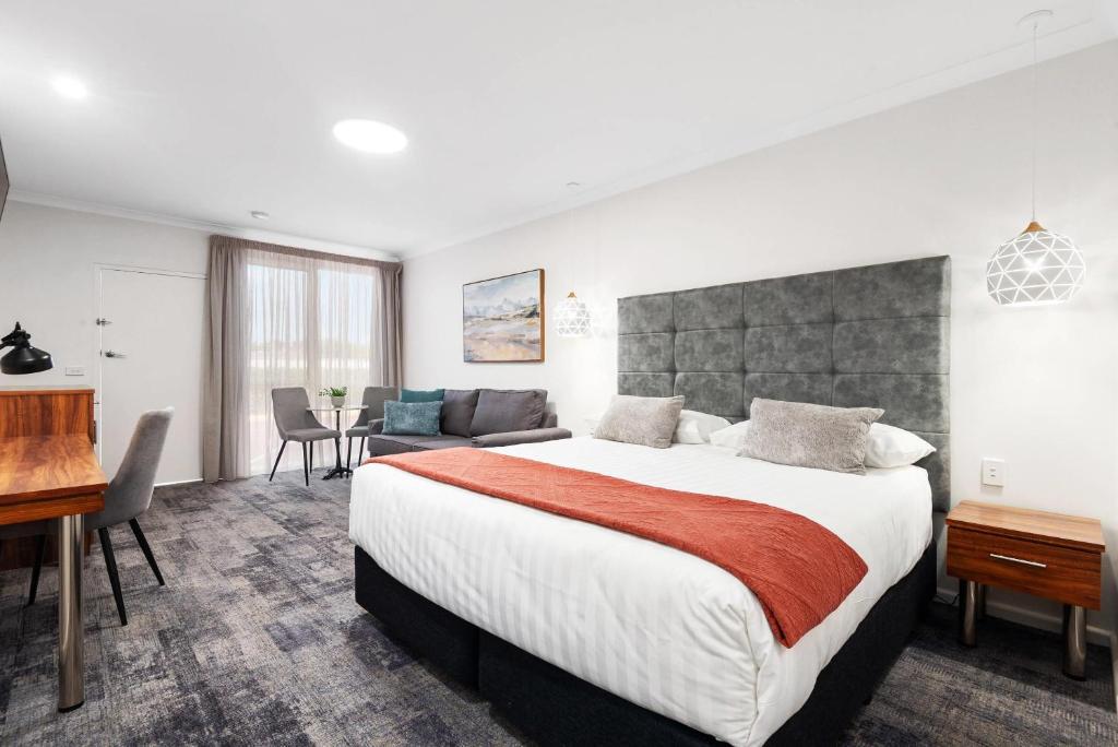 a hotel room with a large bed and a desk at Comfort Inn Deakin Palms in Mildura