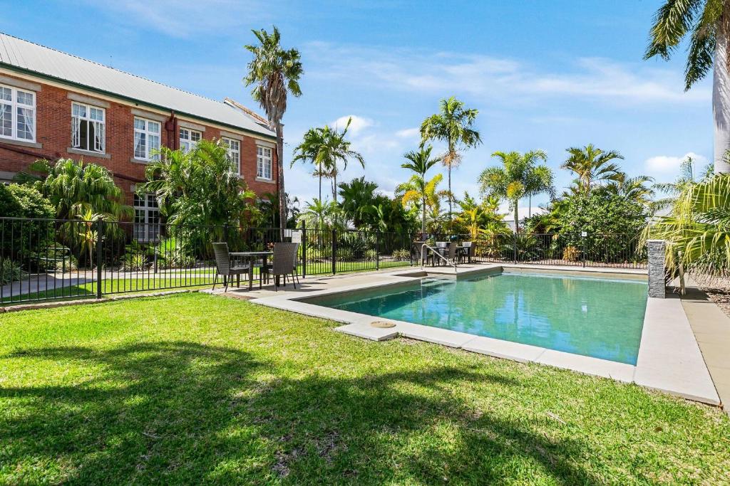 a swimming pool in front of a building with palm trees at Quality Hotel Regent Rockhampton in Rockhampton
