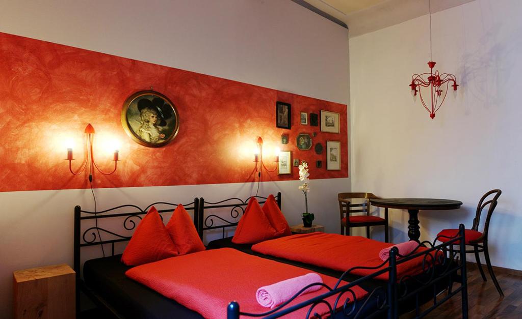 a bedroom with two beds with red pillows and a table at Pension Jeske Heidelberg in Heidelberg