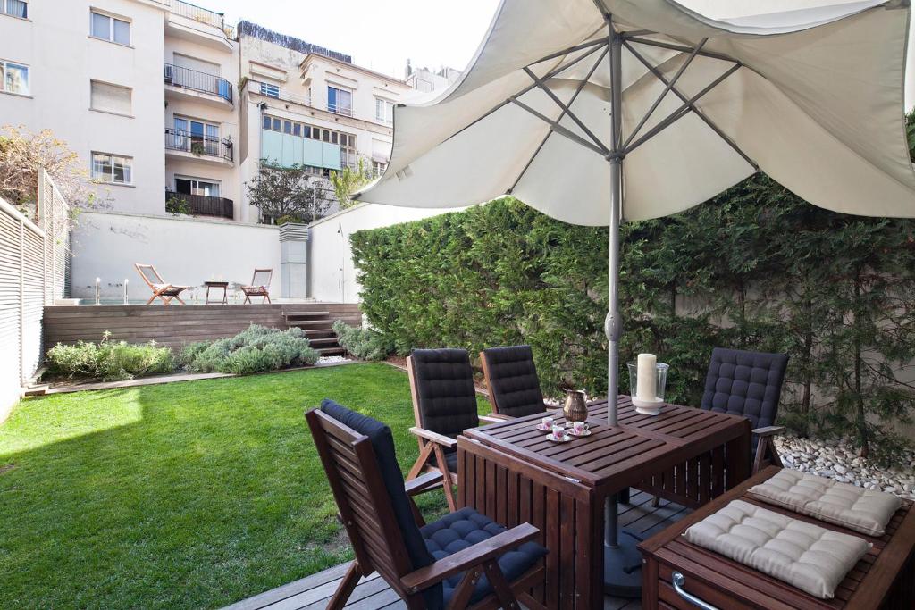 eine Terrasse mit einem Sonnenschirm, einem Tisch und Stühlen in der Unterkunft Apartment Barcelona Rentals - Private Pool and Garden Center in Barcelona