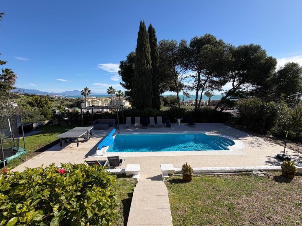 a swimming pool in a yard with trees and a house at 5 Bedroom Villa with HEATED Pool with breath-taking Sea Views, Walking distances to Shops Restaurants Beach in Manilva
