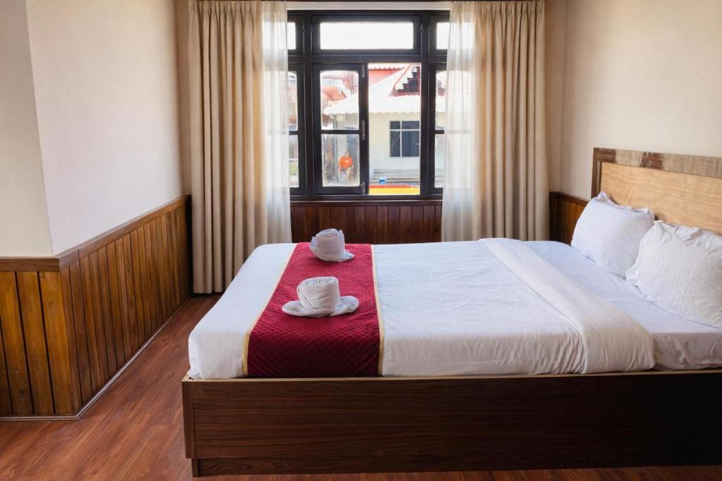 a bedroom with a bed with two hats on it at Hotel Tashiling Stay in Pelling