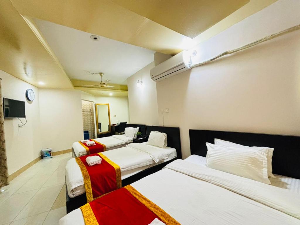 a hotel room with four beds and a tv at Hotel Progati Inn Ltd. in Dhaka
