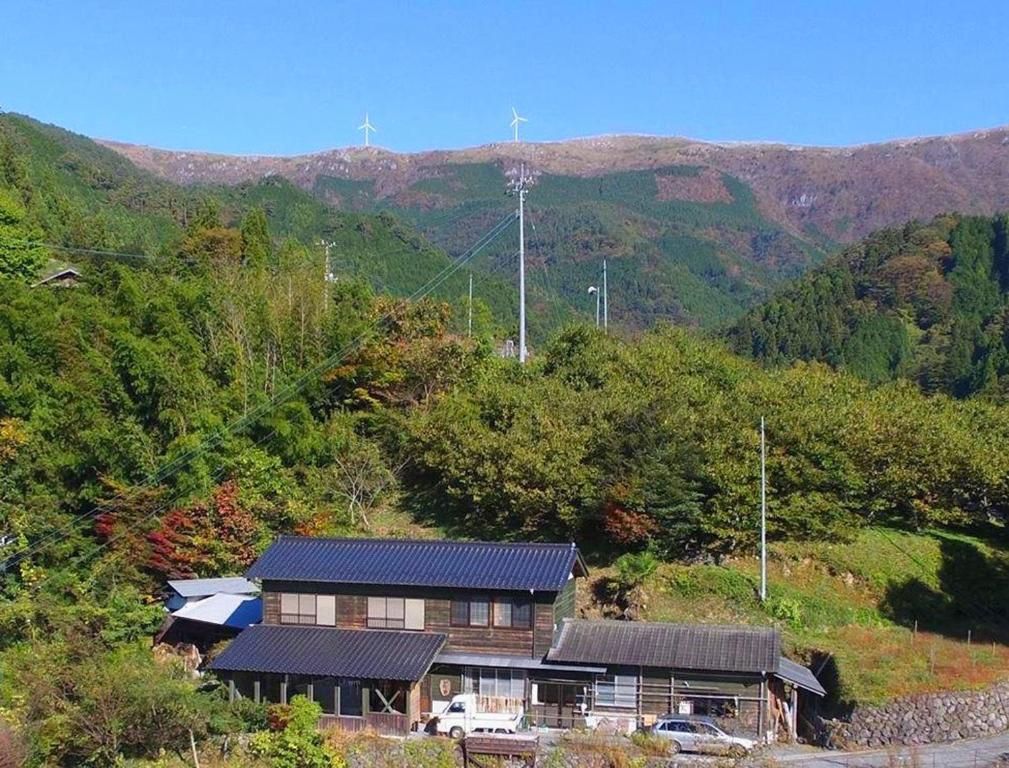 a house on a hill with mountains in the background at Guesthouse Kamikoya ゲストハウス かみこや in Yusuhara