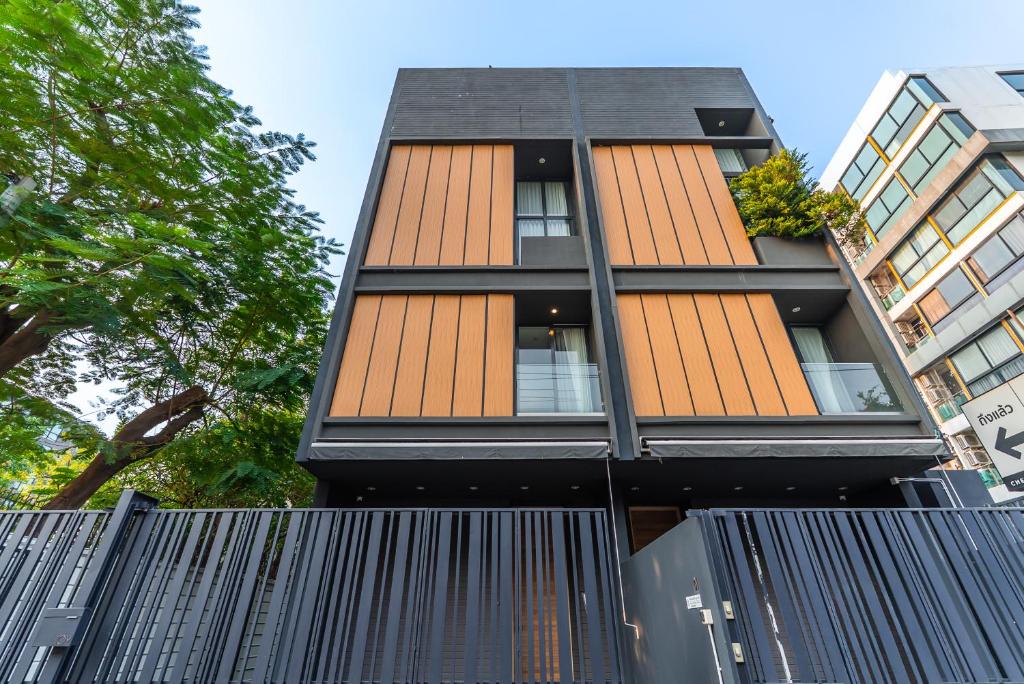 a building with orange and black windows and a fence at Heaven Sukhumvit 62Villa in Bangkok