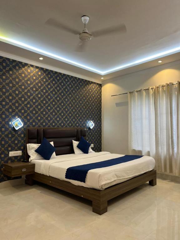 a bedroom with a large bed with blue pillows at Hotel Ashok Palace in Agra