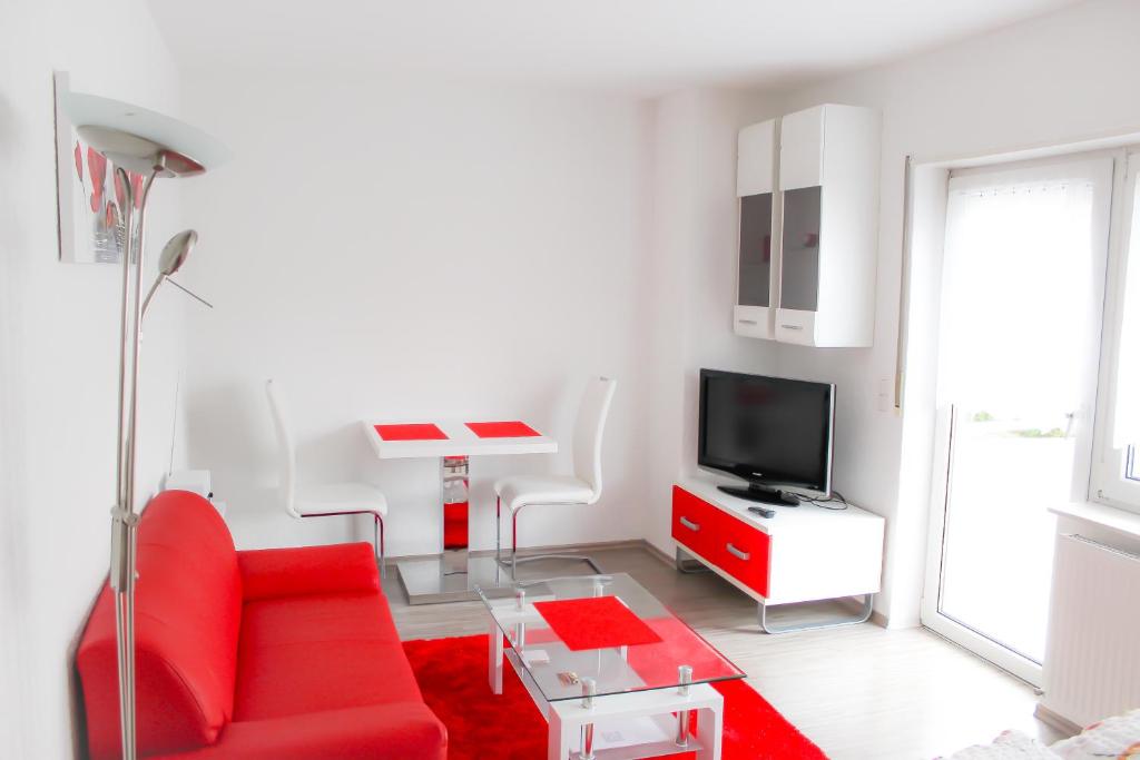 a living room with a red couch and a tv at Ferienwohnung Schwalbennest in Kronau