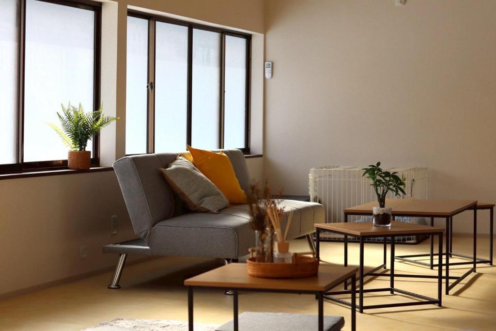 a living room with a couch and tables and windows at TOHANA Style ペット宿泊可能 カラオケルーム有り in Hanamaki