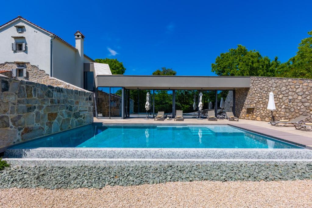 a swimming pool in front of a house at Luxury Jerini House with pool and wellness in Bajčići