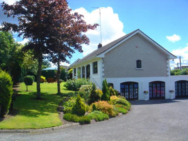 una casa blanca con un árbol y una entrada en Athlumney Manor Guest Accommodation en Navan