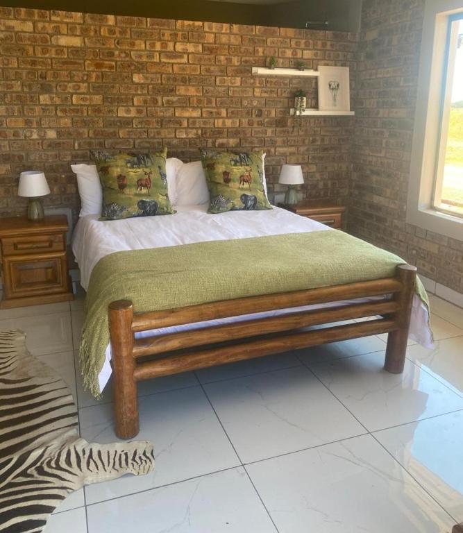 a bedroom with a bed and a brick wall at Little Amanzi in Pienaarsrivier