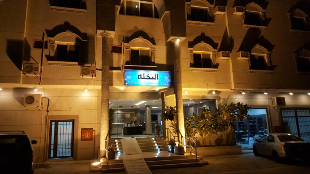 a building with a sign on the front of it at night at Al Nakhlah Furnished Units in Al Hofuf