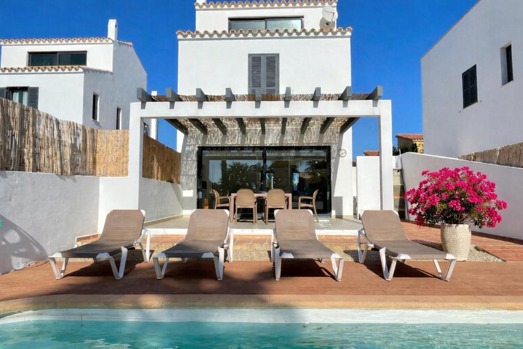 a villa with a swimming pool and chairs and a house at Villa Son Blanc 5 in Sa Caleta