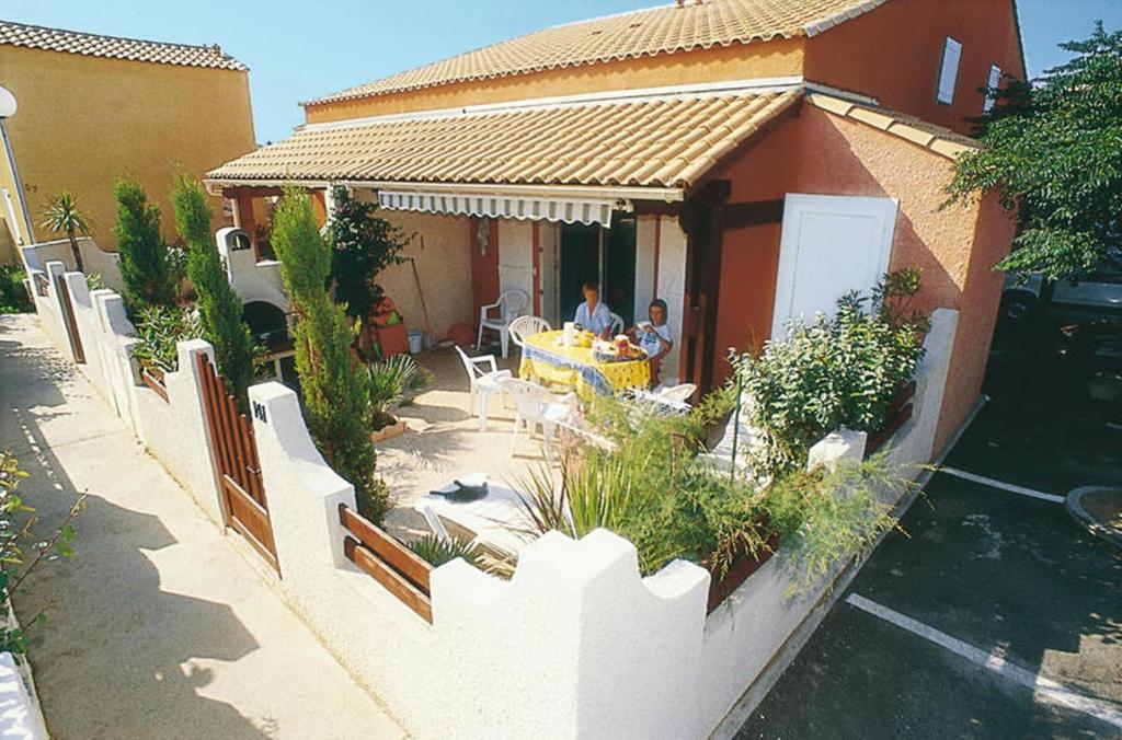 a man sitting at a table outside of a house at HOLIDAYLAND BAIE DES OLIVIERS VILLA 36m2 1chambre fermée 6 couchages ou VILLA 41M2 2chambres fermées 7 couchages in Narbonne-Plage