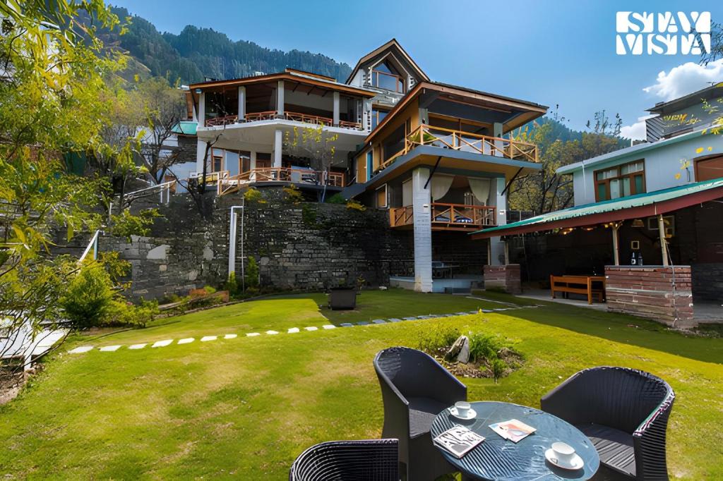 a house on the side of a hill with a yard at Stayvista at Tulip Terraces Cozy Mountain Home with Fireplace in Manāli