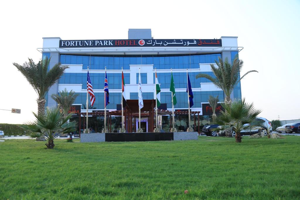 a building with flags in the grass in front of it at Fortune Park Hotel in Dubai