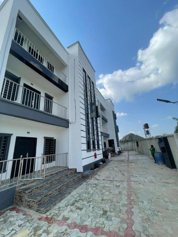 a white building with a stone walkway in front of it at 6c Apartment in Port Harcourt