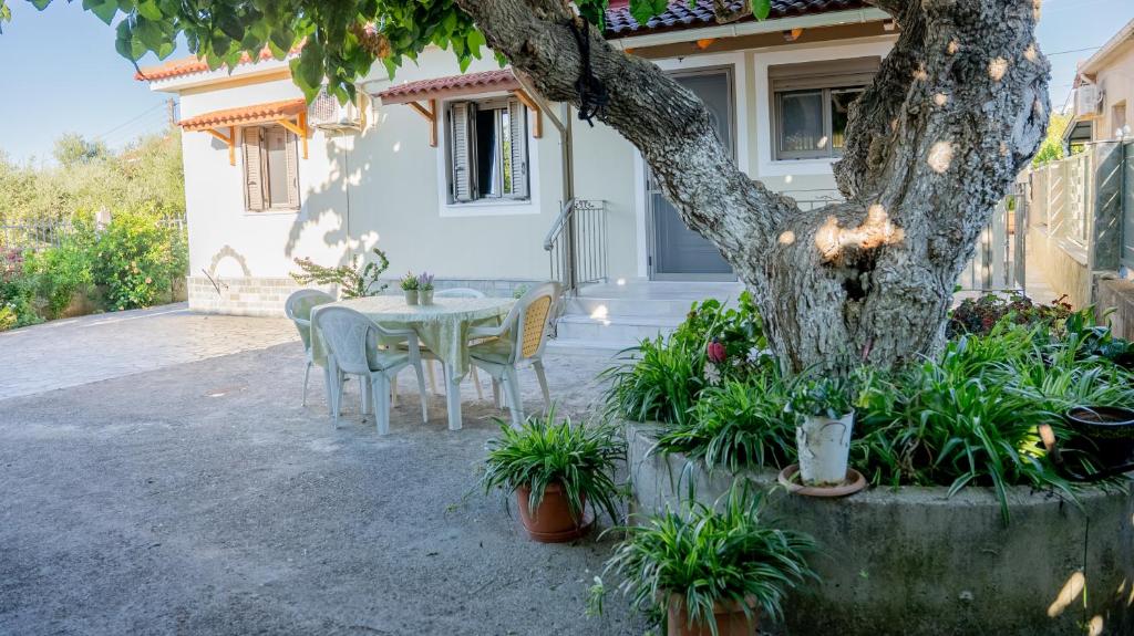 a table and chairs in front of a house with a tree at Η Αυλή της Μαρίας in Áyios Thomás