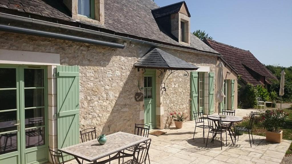 a patio with tables and chairs in a building at Les Bouyssières in Creysse