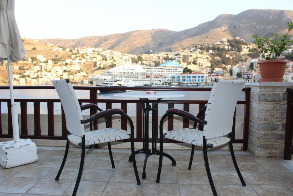 three chairs and a table on a balcony with a view at Odyssia in Symi