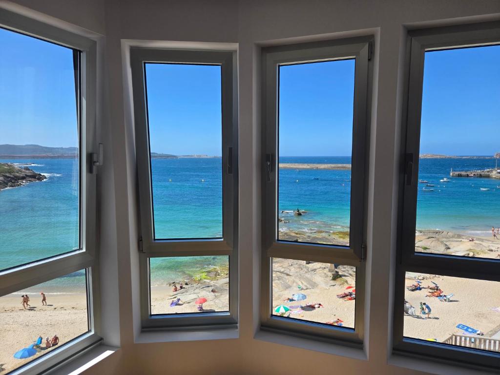 a room with four windows with a view of the beach at C&C Suite in San Ciprián