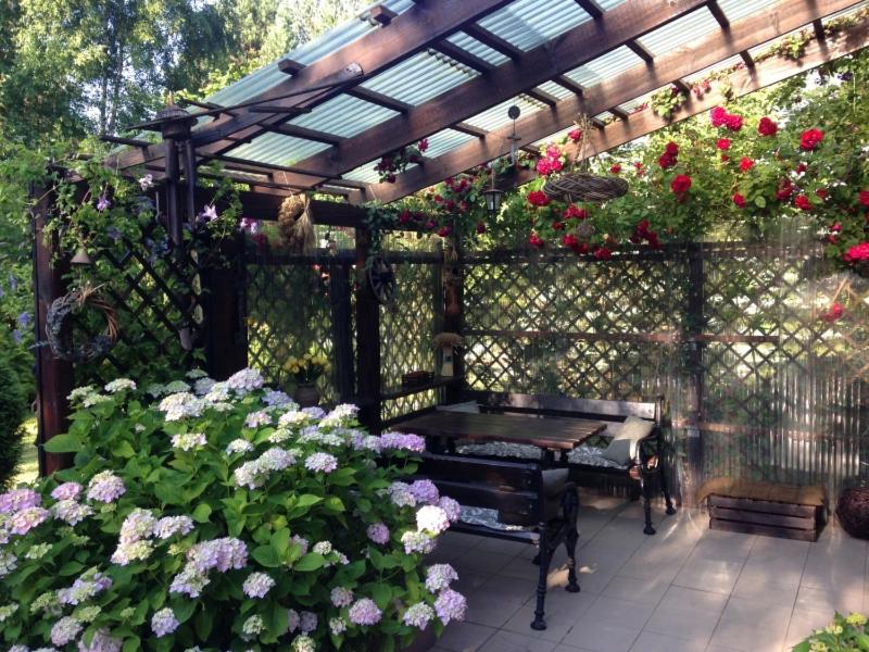 een houten pergola met een bank en wat bloemen bij Family House Gowidlino in Gowidlino