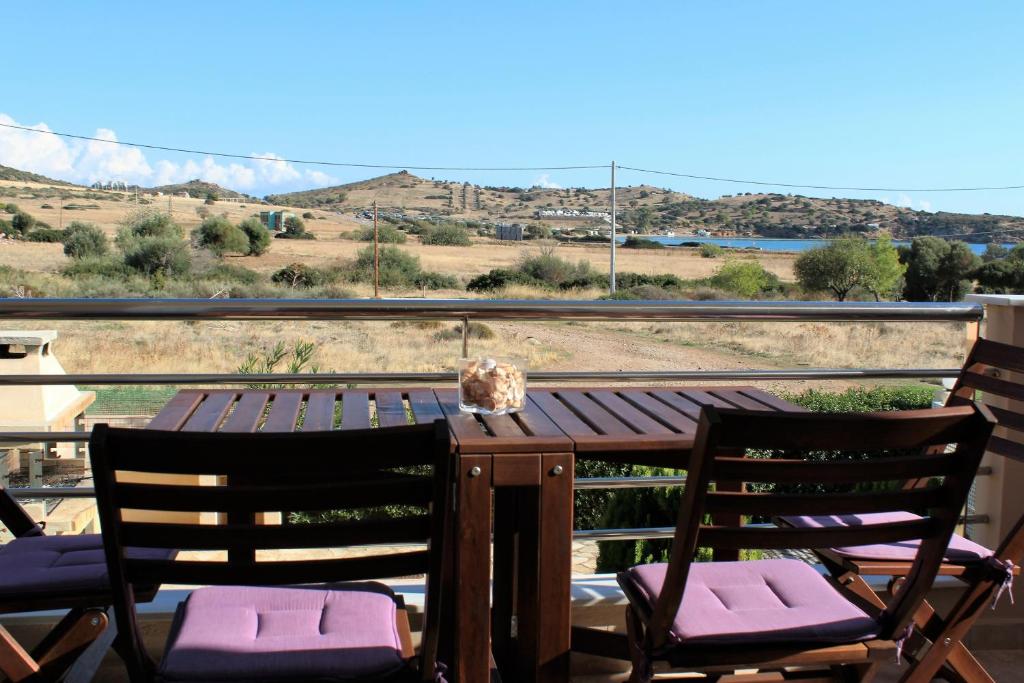 a wooden table with chairs and a view of the mountains at Helen's Sounio Apartments in Sounio