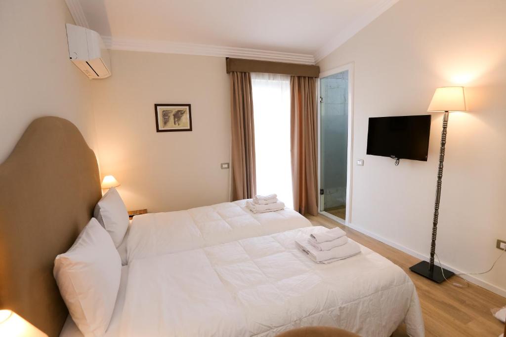 a bedroom with a white bed and a television at Hotel Hermes Tirana in Tirana