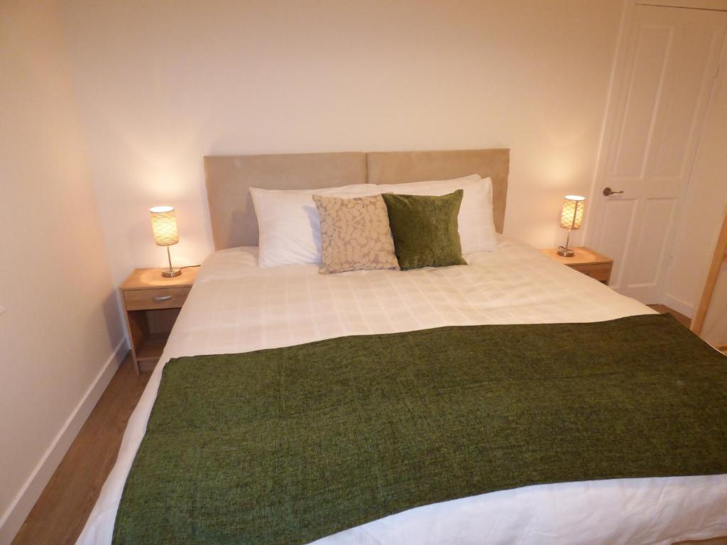 a bedroom with a large bed with two lamps at M9 Falkirk Apartment in Falkirk