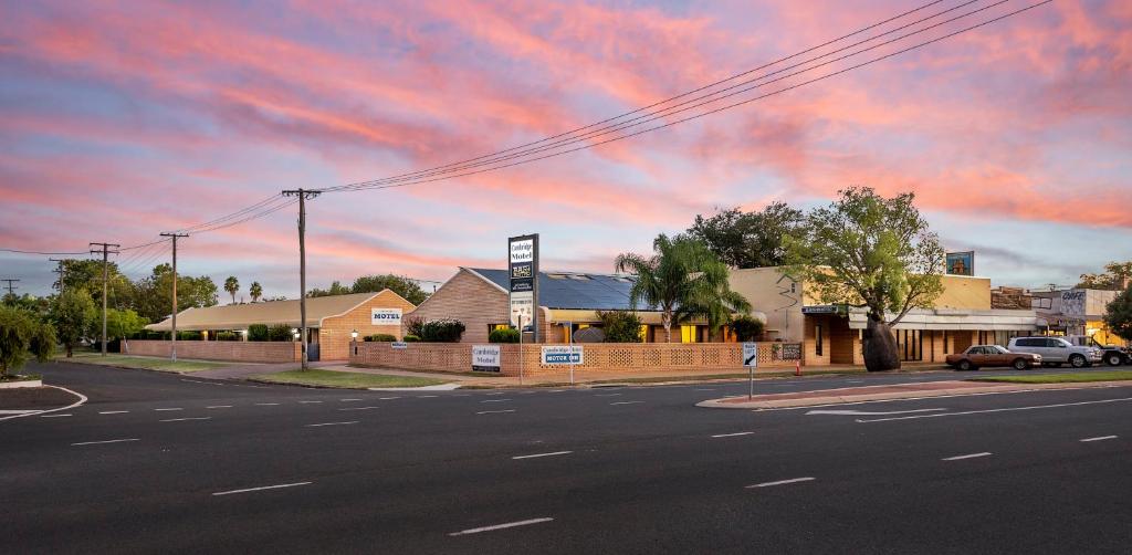 an empty street in front of a building with a cloudy sky at Cambridge Motel in Mitchell
