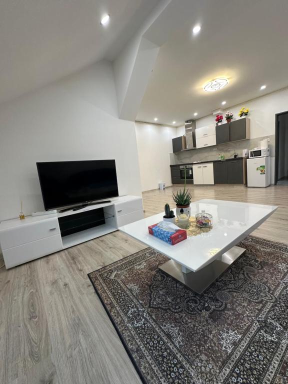 a living room with a white table and a flat screen tv at Apartmány Tonny in Jáchymov