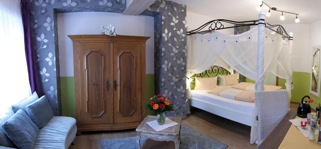 a bedroom with a canopy bed and a couch at Kreuzerhof Hotel Garni in Rothenburg ob der Tauber