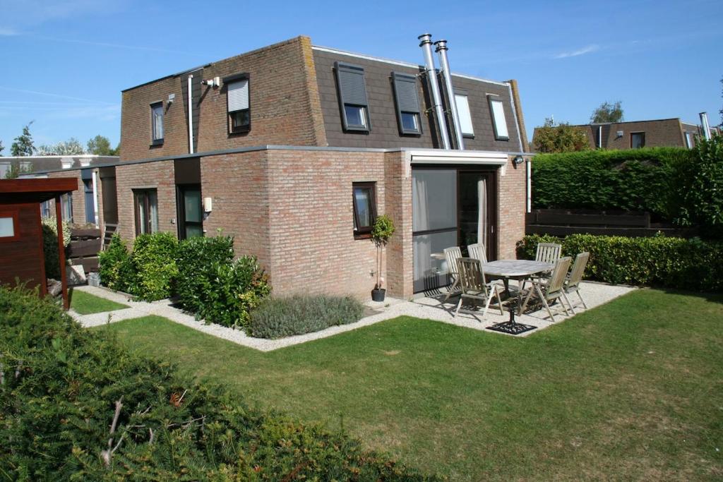 a brick house with a table and chairs in the yard at Heggerank 3A in Nieuwvliet