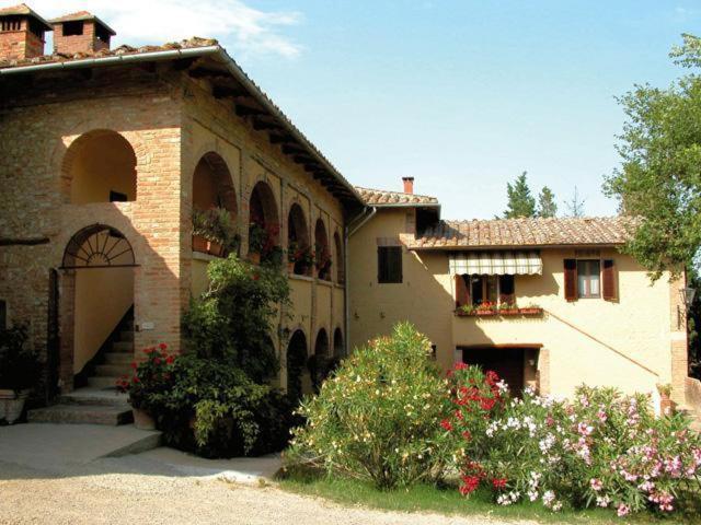 a large brick building with a gate and flowers at Agriturismo Casanova in Asciano