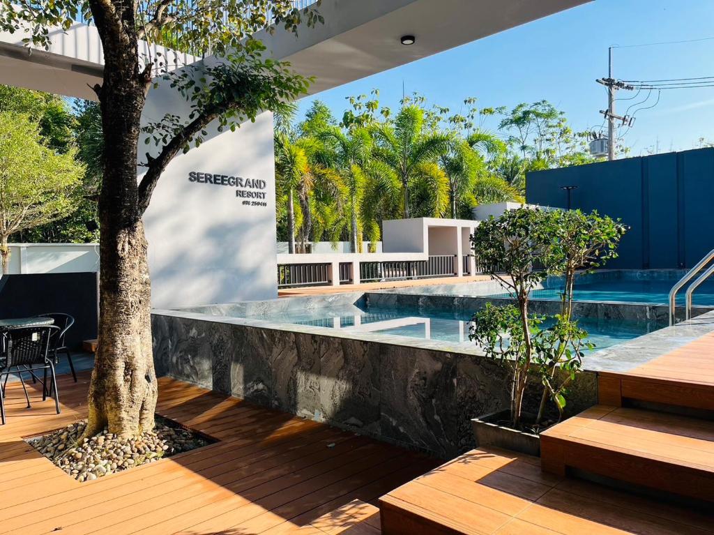 an external view of a swimming pool with a tree at Seree Grand Resort in Hat Yai