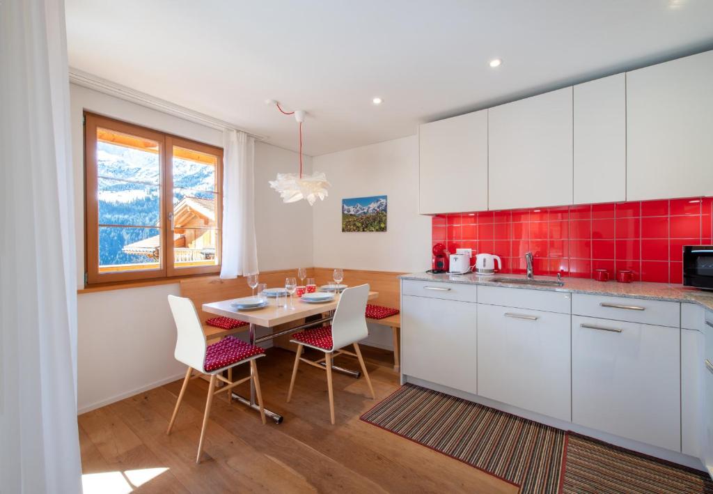 a kitchen with white cabinets and a table with chairs at Panoramapark Soleil E 3 in Wengen