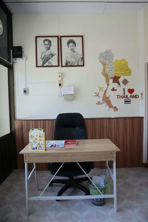a wooden desk with a chair and pictures on the wall at HOM's HOSTEL in Phuket