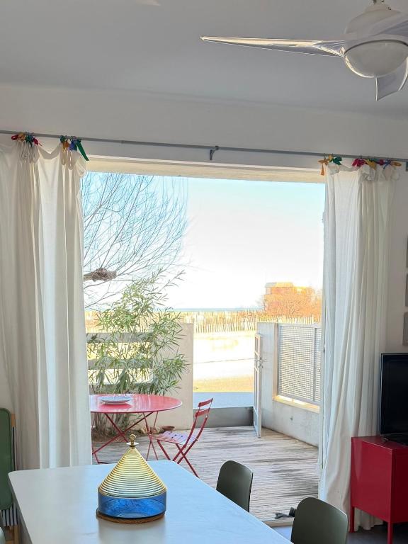 a room with a table and a view of a patio at Vue Mer - appartement de charme - accès direct plage in Leucate-Plage