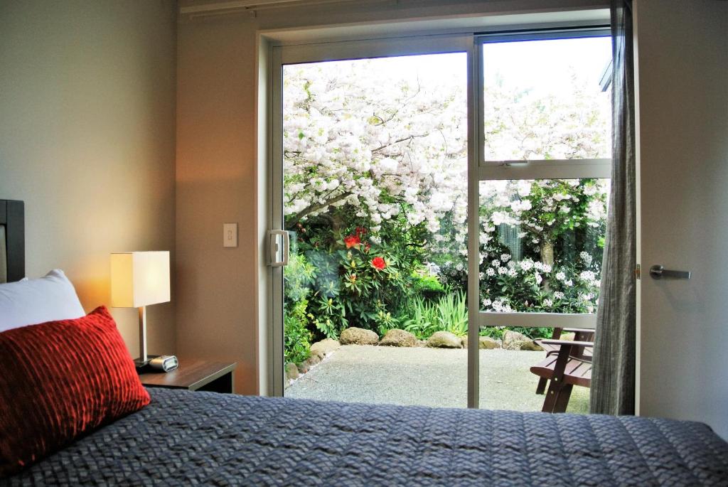 a bedroom with a bed and a door to a garden at Oxford Village Motels in Oxford