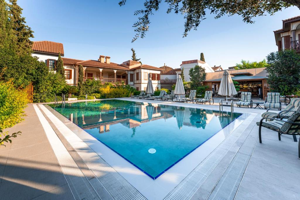 a swimming pool with chairs and umbrellas next to a house at RuinAdalia Hotel in Antalya