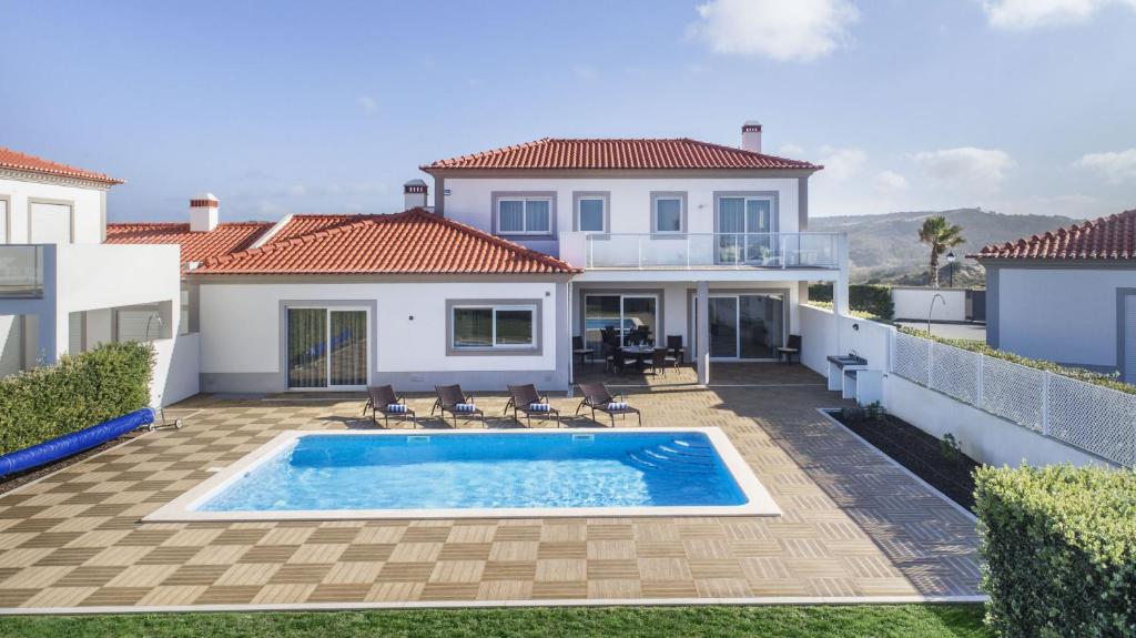 a villa with a swimming pool in front of a house at Villa del Rey II in Casal da Lagoa Seca