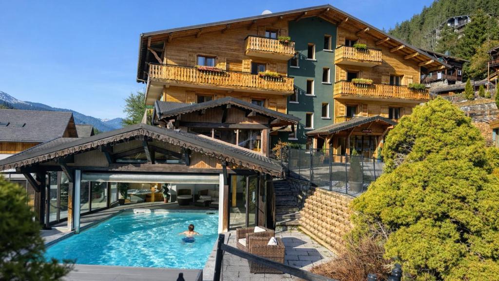 a man in a swimming pool in front of a building at L'Hermine Blanche in Morzine