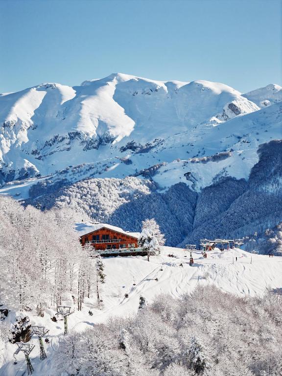 a ski lodge in the snow with mountains in the background at Chalet Morel 1586 Hotel & Spa in Limone Piemonte