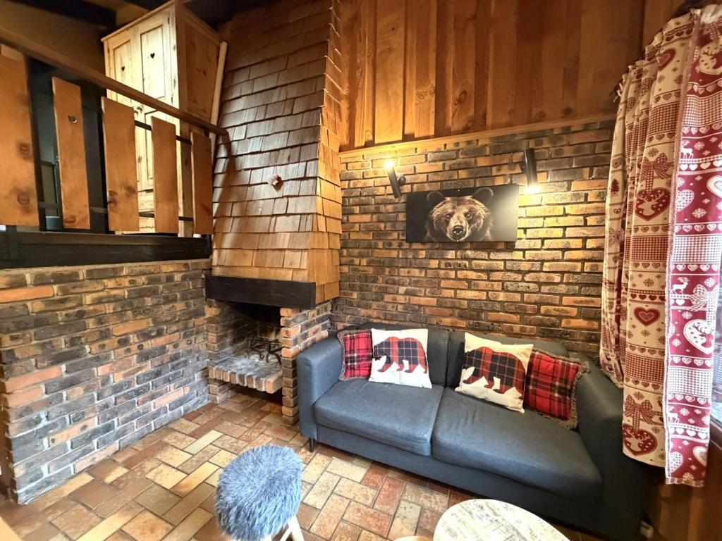a living room with a couch and a brick wall at LA POMME DE PIN 1 Appartement avec terrasse in La Bresse