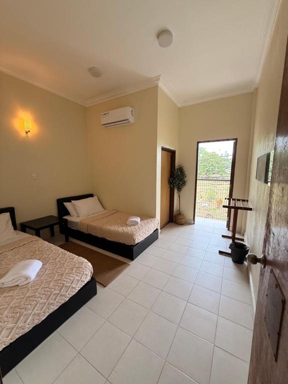 a bedroom with two beds and a door to a balcony at Summer village in Kampong Pasir Hantu