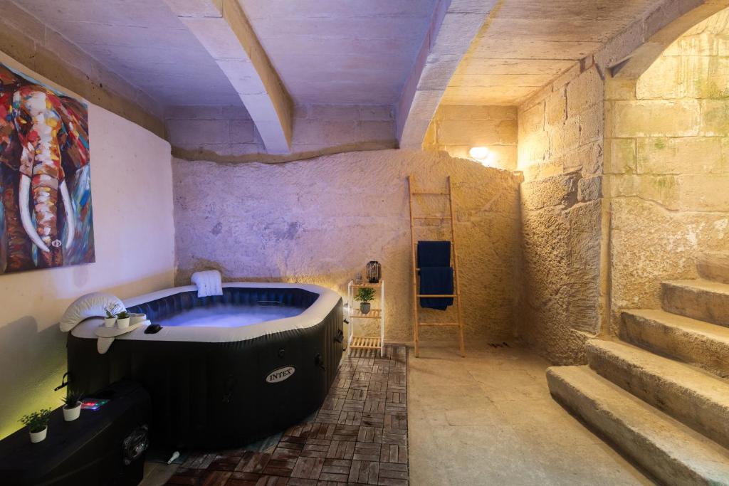 a bathroom with a bath tub in a stone wall at Traditional Maltese 2-Bedroom Home with Private Hot Tub - Steps Away from Valletta in Il-Furjana